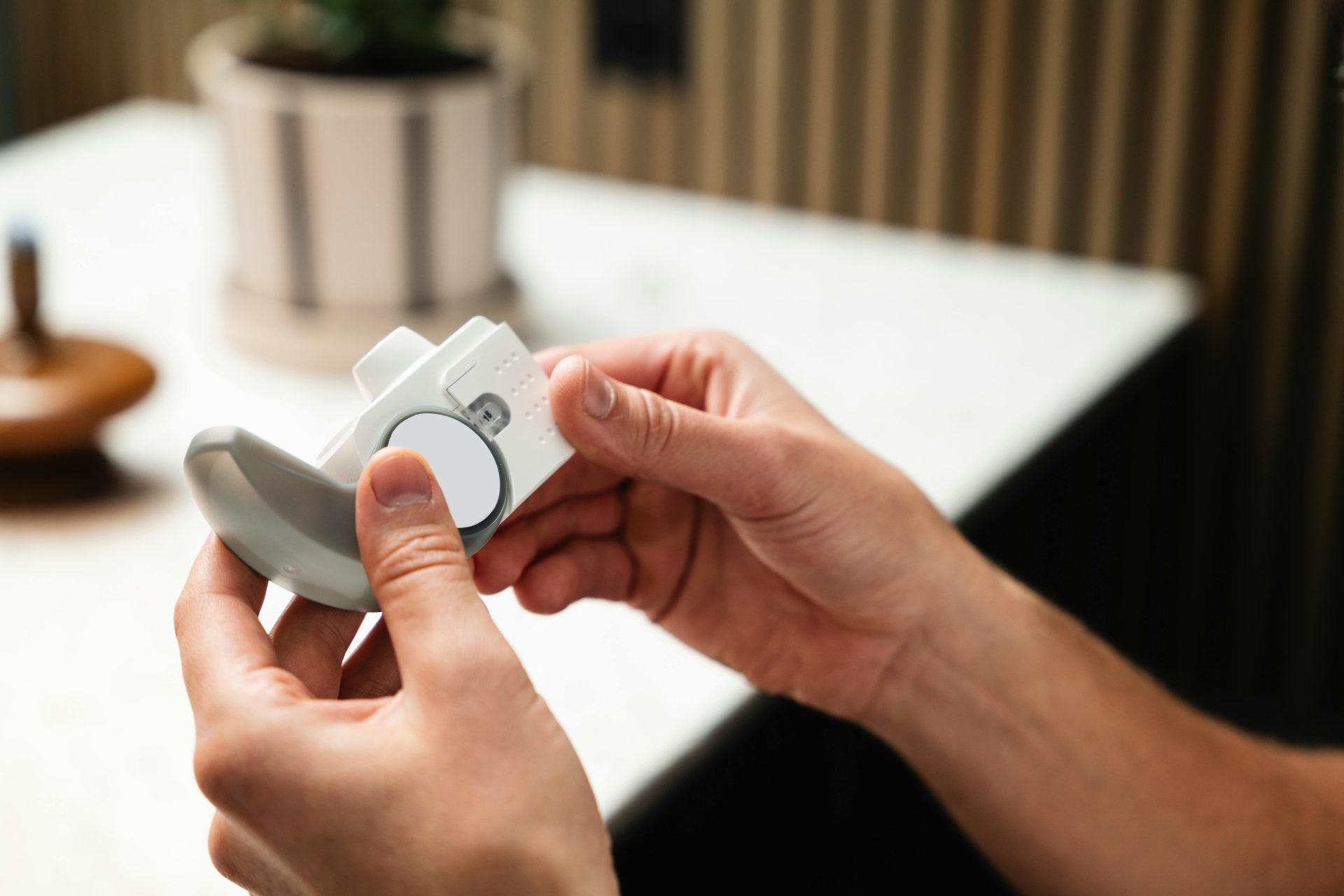 Close-up of hands holding an asthma inhaler, indoors in a modern setting.